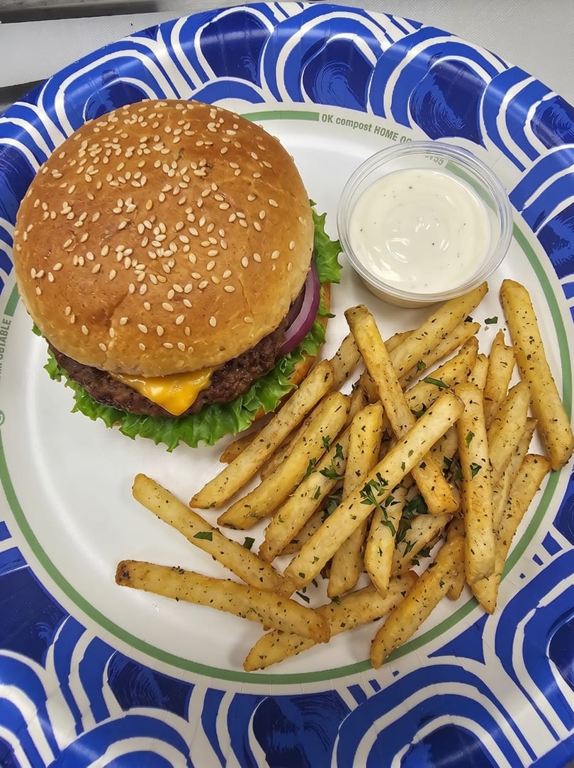 Cheeseburger with lettuce, onion, and sesame seed bun, served with seasoned fries and dipping sauce.